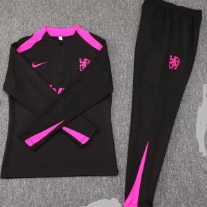 Chelsea tracksuit - Snygg svart träningströja från Nike med rosa detaljer och dragkedja vid halsen. Perfekt för sportiga aktiviteter. Tröjan har långa ärmar och ett stilrent lejonmärke på bröstet.