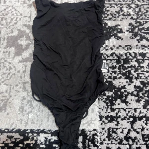 Svart body - Snygg svart body med smala axelband och dekorativa snören på baksidan. Tillverkad i mjukt och stretchigt material för en bekväm passform.