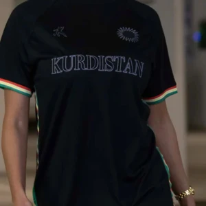Svart fotbollströja med Kurdistan-tryck - Snygg svart fotbollströja med texten 'Kurdistan' i guld på bröstet från LAIB som är trendig på TikTok. Tröjan har korta ärmar med ränder i rött, vitt och grönt. Perfekt för fotbollsfans som vill visa sitt stöd. Använd en gång för att testas enbart. Funkar för både tjejer och killar!! Skriv för mer info