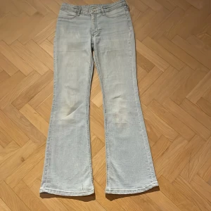 Ljusblå utsvängda jeans från H&M - Säljer ett par ljusblå jeans från H&M med utsvängda ben och låg midja. De har en justerbar midja och klassisk femficksdesign. Storlek 152, innerbenslängd 70 cm, midjemått 33cm (från kant till kant)