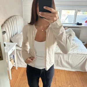 Beige kofta från by Ti Mo - Säljer en stilren beige kofta från by Ti Mo i storlek S. Koftan har långa ärmar och knappar framtill, perfekt för en avslappnad look. Den är tillverkad i ett mjukt material som känns skönt mot huden.  Med fina detaljer😝