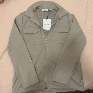 Zip overshirt - Säljer en stilren beige zip overshirt från Only & Sons aldrig använt bara testat skick 10/10. Den är storlek XS men är stor i storleken så passar dom som är runt 170-180. Riktig fett och varmt, hör av er vid frågor.