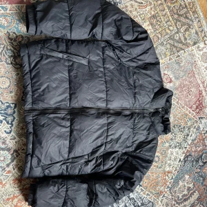 Svart/marinblå pufferjacka från Everest - Säljer en svart pufferjacka från Everest i storlek L. Jackan har en dragkedja framtill och är perfekt för kyligare väder. Den är långärmad och har en klassisk pufferdesign som ger både stil och värme. Använd ca 2-3 gånger. (går att pruta!!!!)