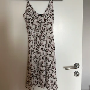 Blommig klänning från Yoins - Söt blommig klänning från Yoins i vitt med rosa blommor. Klänningen har en smickrande passform med smala axelband och en lätt utsvängd kjol. Använd en gång, se bilden.