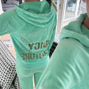 Mintgrönt velour sätt från Juicy Couture - Säljer ett mintgrönt sätt i mjuk velour från Juicy Couture med guldglittrig text på ryggen och benet. Tröjan har dragkedja framtill, huva och fickor. Byxorna är i storlek S och Tröjan i XS men sitter mer som en S