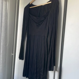 Svart långärmad klänning med zebramönster - Säljer en svart långärmad klänning med subtilt zebramönster och draperad urringning. Klänningen har en smickrande passform och är perfekt för dig som gillar stilrena detaljer med en twist.