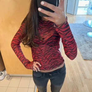 Röd och svart zebramönstrad långärmad topp - Säljer en långärmad topp med rött och svart zebramönster. Tight passform och hög hals, perfekt för att sticka ut. Tunn och stretchig, passar till både jeans och kjol. Supercool och trendig vibe! Tror den e från Zara