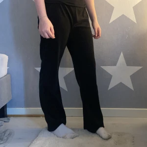 Svarta byxor från Gina Tricot - Svarta byxor från Gina Tricot med vida ben och hög midja. Byxorna har två metallöljetter framtill i midjan och är tillverkade i ett mjukt material som ger en bekväm känsla. Perfekta för en avslappnad och stilren look.