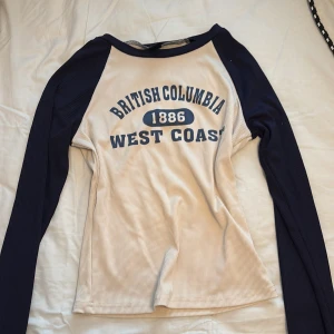Långärmat med tryck  - Säljer en beige och marinblå långärmad tröja med texten 'British Columbia 1886 West Coast' framtill. 