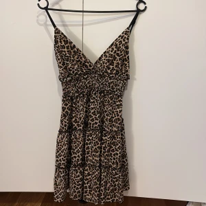 Leopardmönstrad kortklänning med smala axelband - Säljer en snygg kortklänning med leopardmönster och smala axelband. Klänningen har v-ringad hals och resår i midjan för en bekväm passform. Perfekt för dig som gillar leopard mönster!❤️❤️