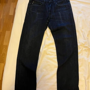 Stone island Jeans - Säljer ett par mörkblå jeans från Stone Island med klassisk femficksdesign och raka ben. Jeansen har en enkel look utan slitningar och tydliga sömmar. Perfekta för dig som gillar stilrena och tidlösa jeans. Bra skick, men saknar badge och knappar till badgen. Midja 32