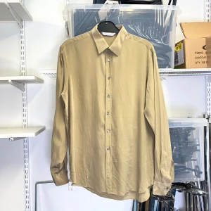 Beige sidenskjorta - Stilren beige sidenskjorta med klassisk krage och knäppning framtill och långa ärmar.  Strl: M. Mått: Ärmlängd från axel 64 cm.  /  Spara skärmtid, besök våra butiker i Sthlm, Malmö & Gbg. New arrivals daily + studentrabatt i alla våra butiker! Hitta till din närmsta butik på humansecondhand.se.   HUMANA Second Hand erbjuder 14 dagars retur, även via plick. Returer skickas med PostNord. Vid retur kontakta support@plick.se.