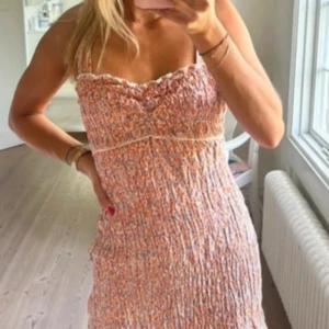 Blommig smockad Zara  - Supersöt blommig klänning med smockad överdel. Klänningen har en figurnära passform och små volangdetaljer upptill. Perfekt för varma dagar och somriga tillfällen. Jättefin orange/rosa ”bakgrund” med blå små blommor på. Priset kan diskuteras💞💞