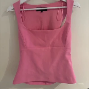 Rosa topp från Zara - Säljer en snygg rosa topp från Zara med breda axelband och fyrkantig urringning. Toppen är figurnära och har en stilren design som passar perfekt till sommaren. Materialet känns mjukt och bekvämt mot huden.