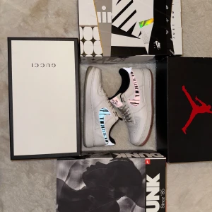 Nike Air Force 1 med zebra-detaljer - Unika Nike Air Force 1 med vit bas och färgglada zebramönstrade swooshes i blått och rosa. Skorna har reflekterande detaljer, svart innerfoder och specialdesignade innersulor med mönster. Perfekt för dig som vill sticka ut med din stil.