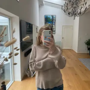 Säljer en stilren beige omlottkofta från NA-KD designad av Hanna Schönberg. Koftan har långa ärmar och ett knytband i midjan för en justerbar passform. Perfekt för lager-på-lager under kyligare dagar. Den har öppen rygg.