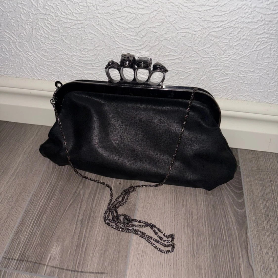 Svart handväska med kedjerem och dekorerat handtag