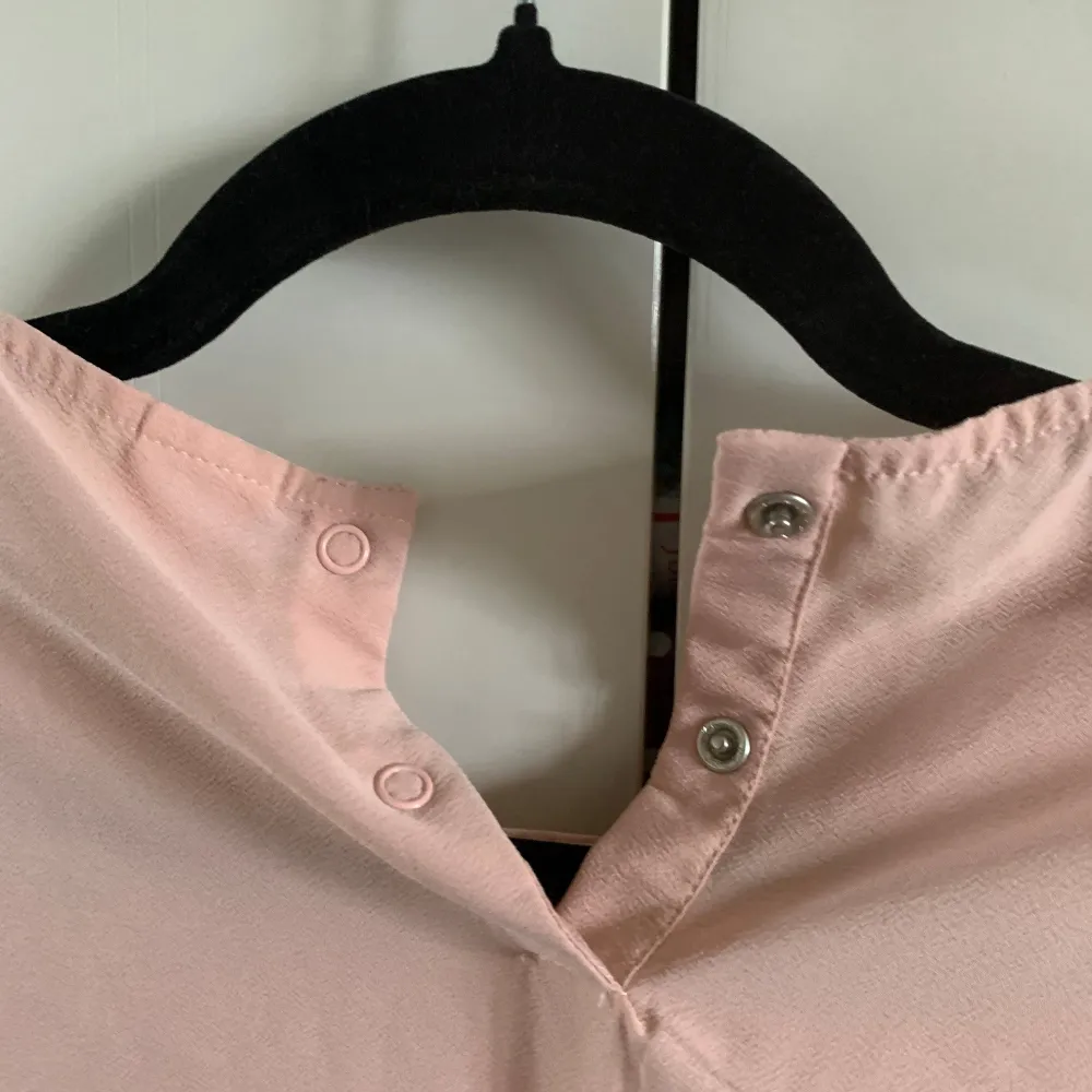 Säljer en ljusrosa blus från Lindex med snygga volangärmar och snörning framtill. Blusen har långa ärmar och knäppning i nacken. Perfekt för dig som gillar romantiska detaljer och en feminin stil. stor i storlek så 34 36 fungerar. Puserot.