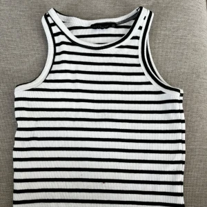 Randig ribbad linnetopp  - Säljer en ribbad linnetopp i svart och vitt med klassiskt horisontellt randigt mönster. Toppen är ärmlös med rund halsringning och har en jätte liten liten fläck framtil som knappt syns. 