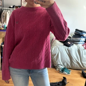 Rosa kabelstickad tröja från GANT - Säljer en rosa kabelstickad tröja från GANT i 100% lammull. Tröjan har rund halsringning, ribbade muddar och lång ärm. 