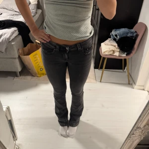 Svarta bootcut jeans från Gina  - Snygga svarta jeans från Gina med bootcut passform och låg midja. Jeansen har även fickor med knappar baktill. Materialet är slitstarkt jeans och färgen är mörkgrå/svart.