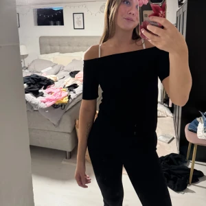 Svart offshoulder topp - Säljer en svart offshoulder topp med korta ärmar. Snygg och enkel design som sitter tight och framhäver axlarna. Perfekt för dig som gillar stilrena plagg med lite edge. Materialet känns mjukt och stretchigt mot huden.