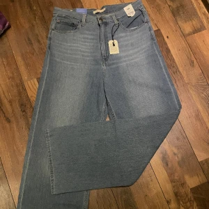Levis High Loose Jeans Blå - Ett par oanvända Levi’s Jeans som jag köpte som jag trodde skulle passa men inte gjort och har sedan bara legat i min garderob dom senaste månaderna. ÖPPEN FÖR PRISFÖRSLAG                                          Bild 1-3 är från förra säljaren, 4 är tagen från mig men fortfarande samma skick och produkt som när jag fått dom och bild 5 är för att se tydligare evilken färg