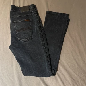 Svarta jeans från Nudie Jeans - Säljer ett par svarta jeans från Nudie Jeans. Modell grim tim. Inga defekter på dem, väl använda dock men fortfarande ett par riktigt stilrena och tidlösa jeans. De sitter rätt så slim och är 30/31 i midjan och längd. Så de är lite stora i storleken. 
