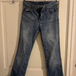 Blåa Armani Jeans bootcut - Snygga blå jeans från Armani Jeans med klassisk femficksmodell och bootcut-ben. Jeansen har ljus tvätt och ikonisk AJ-logga i metall på bakfickan. Tillverkade i mjukt denimtyg som ger en skön känsla och stilren look. Finns även en sprättming i ljumsken, men går att fixa.