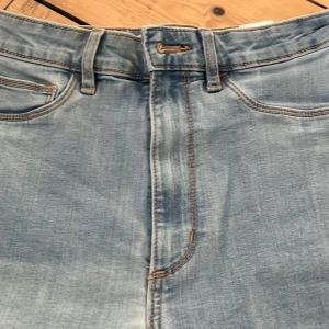 Ljusblå bootcut jeans - Snygga ljusblå jeans med bootcut passform och klassisk femficksdesign. Jeansen har hög midja och är tillverkade i mjukt denimtyg med lite stretch. Perfekta för dig som gillar en retroinspirerad look med raka ben och lätt utsvängd nederdel. Storlek s/32.