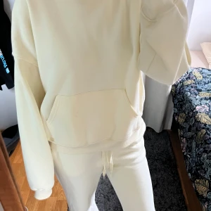 Oversized ljusgul hoodie med huva - Säljer en oversized hoodie i ljusgul färg med stor huva och magficka. Tröjan har långa ärmar och är tillverkad i mjukt bomullsmaterial, perfekt för en chill och avslappnad stil. Passformen är loose och den är superbekväm att bära. Säljer också matchande mjukisbyxor till!! Nästan helt ny!