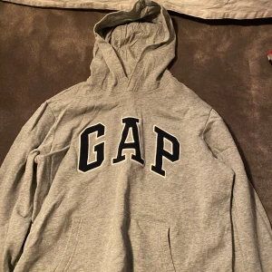 Grå GAP hoodie med huva - Klassisk grå hoodie från GAP, ej använd och säljer pga för liten.