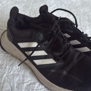 Svarta Adidas sneakers unisex - Svarta Adidas sneakers från Stadium. Kommer inte till användning längre eftersom jag har två. Skosnöret sitter fel