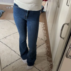 Blå bootcut jeans från &Denim - Snygga blå jeans från &Denim med klassisk bootcut-passform och fem fickor. Jeansen har en hög midja och är tillverkade i mjukt jeansmaterial med lite stretch för extra komfort. Perfekta för dig som gillar retrovibbar och vill ha ett par jeans som sitter riktigt bra.