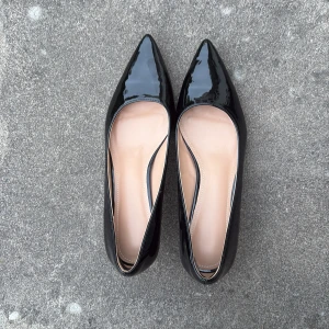 Svarta lackade pumps med spetsig tå - Oanvända, snygga svarta pumps i lack med spetsig tå och låg klack. Skorna har en klassisk och elegant form med beige innersula. Perfekta för dig som vill ha en stilren och trendig look. 
