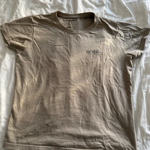 BOSS t-shirt i bomull XS - Snygg ljusbrun t-shirt från BOSS med diskret logga på bröstet. Klassisk rund hals och korta ärmar, perfekt för en chill och stilren look. Tillverkad i mjuk bomull som känns skön mot huden. Passar dig som gillar minimalistisk design och vill ha ett cleant plagg i garderoben.