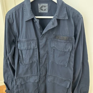 Chesapeakes US Army overshirt - Säljer en grymt snygg mörkblå overshirt från märket Chesapeakes. Köptes nypris för 3500 på klädesbutiken i Båstad (https://www.markesbutiken.se/shop/search?s=Chesapeakes) Knappt använd så väldigt bra skick. Hör av er vid frågor eller för mer bilder