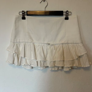 Volangkjol Zara - Volangkjol från zara köpt förra året. Den är cremevit och har ett litet metall spänne framtill. Har en volangkant längst ned. Storlek M på lappen men jag skulle säga att den sitter mer som en S. Den sitter lågmidjat.  Midja: 40 cm mätt platt Längd: 30/31 cm