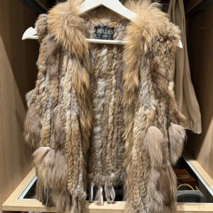Brun pälsväst från Hollies XS - Säljer en fluffig och lyxig pälsväst från Hollies i storlek XS. Västen har en mix av bruna, beige och grå toner med långhårig päls och coola detaljer som tofsar och struktur. Perfekt för dig som vill sticka ut och addera lite edge till din outfit. Äkta päls! Köpt från Hollies i Stockholm 