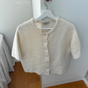 Cream färgad stickad kofta från Gina  - Superfin beige stickad kofta från Gina Tricot med korta ärmar och rund hals. Använd fåtal gånger så jätte fint skick. Pris kan diskuteras🤍