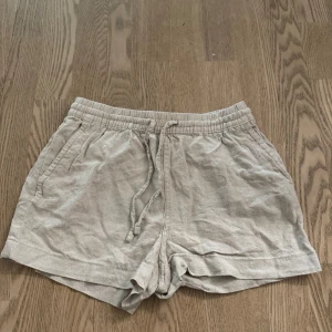 Beige linneshorts från H&M XS - Snygga beige shorts från H&M i linnemix med elastisk midja och snörning. Modellen har två sidofickor. Materialet är luftigt och ger en chill vibe till din outfit. Har eventuellt krymt lite i tvätten men annars har de inte blivit använda så mycket