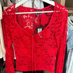 Röd spetsblus från Pieces - Superfin röd långärmad blus i spets från Pieces. Blusen har blommigt mönster, v-ringning och knyt framtill. 
