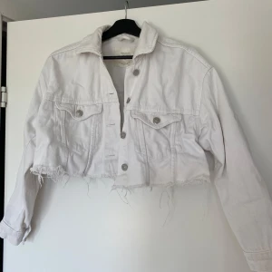 Vit croppad jeansjacka Stradivarius - Säljer en vit croppad jeansjacka från Stradivarius med fransig nederkant. Knappt några tecken på användning, mest skrynklig då den inte är använd på ett bra tag.