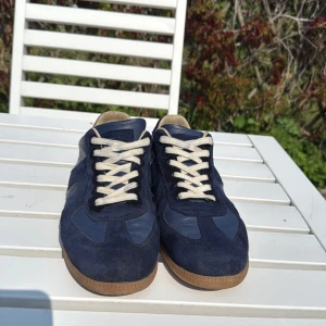 Maison Margiela blå sneakers (Kvitto finns) - Säljer nu mina unika mörkblåa maison margiela gats för att de blivit för små. Köpta på NK, box och kvitto medföljer! Hör av er vid minsta fundering och priset är ej hugget i sten