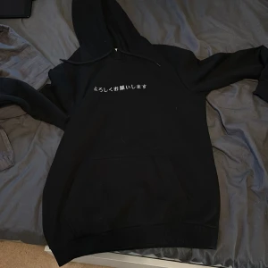 Svart hoodie med japanskt tryck Pier One - Svart hoodie från Pier One med japansk text framtill och en stor vit grafisk drake på ryggen. Klassisk huva med snörning och känguruficka. Perfekt för dig som gillar streetstyle och unika prints. Använd 2 gånger. Ganska relaxed/stor. 