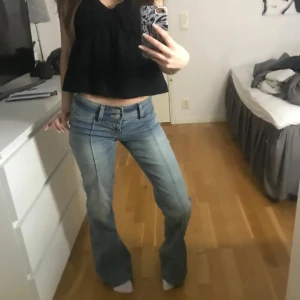Bootcut ljusblå jeans med låg midja - Säljer ett par ljusblå bootcut jeans med låg midja och klassisk femficksdesign. Jeansen har snygga sömmar längs benen och en dubbelknäppning fram. Perfekt passform för dig som gillar en avslappnad och trendig look. Storlek 23/32 men är stora i storleken, uppsydda i benen och passar mig på 160 cm