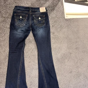 True Religion mörkblå bootcut jeans - Mörkblå jeans från True Religion med bootcut och låg midja. Säljer då de tyvärr inte passar längre, sparsamt använda. Strorlek 26