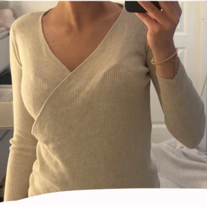 Beige ribbad omlottop - Superfin beige omlottop med ribbad struktur och v-ringning. 