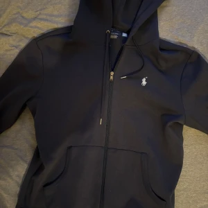 Mörkblå zip hoodie från Polo Ralph Lauren - Snygg mörkblå zip från Polo Ralph Lauren med dragkedja. Sitter lite kort tycker jag, den är i storlek S och jag är 184. Annars i jätte bra skick, som ny nästan.