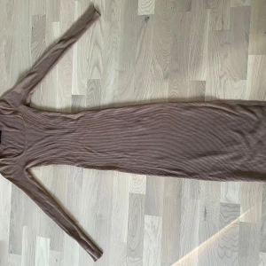 Ribbad brun ankel lång klänning - Säljer denna fina ribbade klänning då den tyvärr är för liten för mig. Den är använd en gång och har inga defekter. Storlek 32 men är väldigt stretchig.